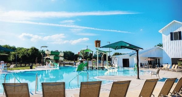 A swimming pool with lounge chairs and a water slide.