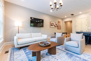 A living room with a sofa, armchairs, a coffee table, and artwork on the walls.