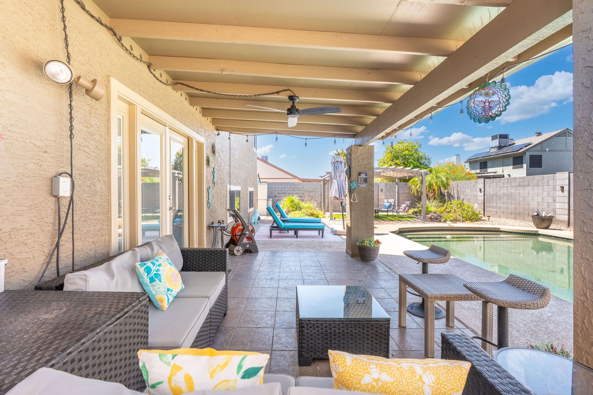 Une terrasse extérieure avec une piscine, un espace salon et une partie abritée.