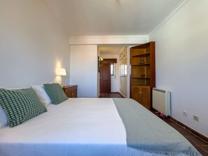 A bedroom with a bed, bedside tables, a wardrobe, and a radiator. - Alto da Villa by Acasadascasas (Mafra)