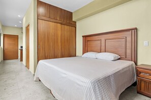 Habitació d'hotel amb un llit gran, un armari de fusta i una taula de nit.