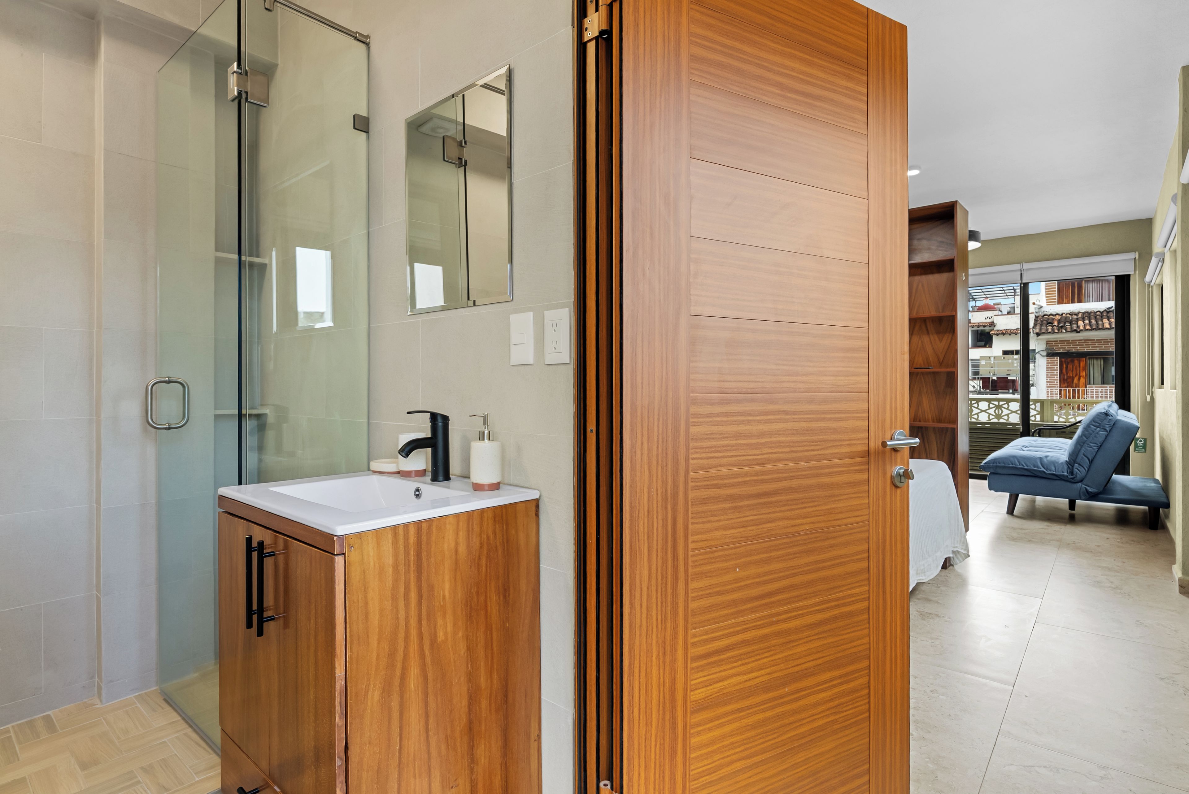 A modern bathroom with a glass shower enclosure, wooden cabinetry, and a sink with a mirror above.
