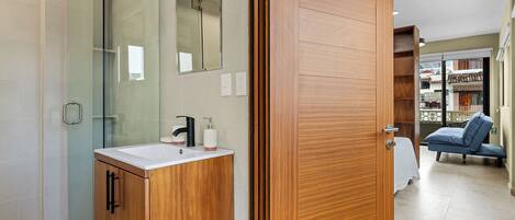 Een moderne badkamer met een douchecabine van glas, houten kastjes en een wastafel met spiegel erboven.