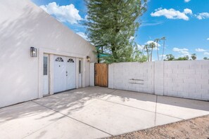 A residential garage with a white exterior, a wooden gate, and a paved driveway. - Phoenix Furnished with 2 Queen Beds & EV Charger! (Phoenix)