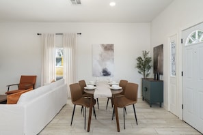 A dining area with a table set for four, surrounded by chairs, a sofa, and a cabinet. - Phoenix Furnished with 2 Queen Beds & EV Charger! (Phoenix)