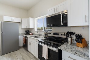 A modern kitchen with stainless steel appliances, white cabinetry, and a granite countertop. - Phoenix Furnished with 2 Queen Beds & EV Charger! (Phoenix)