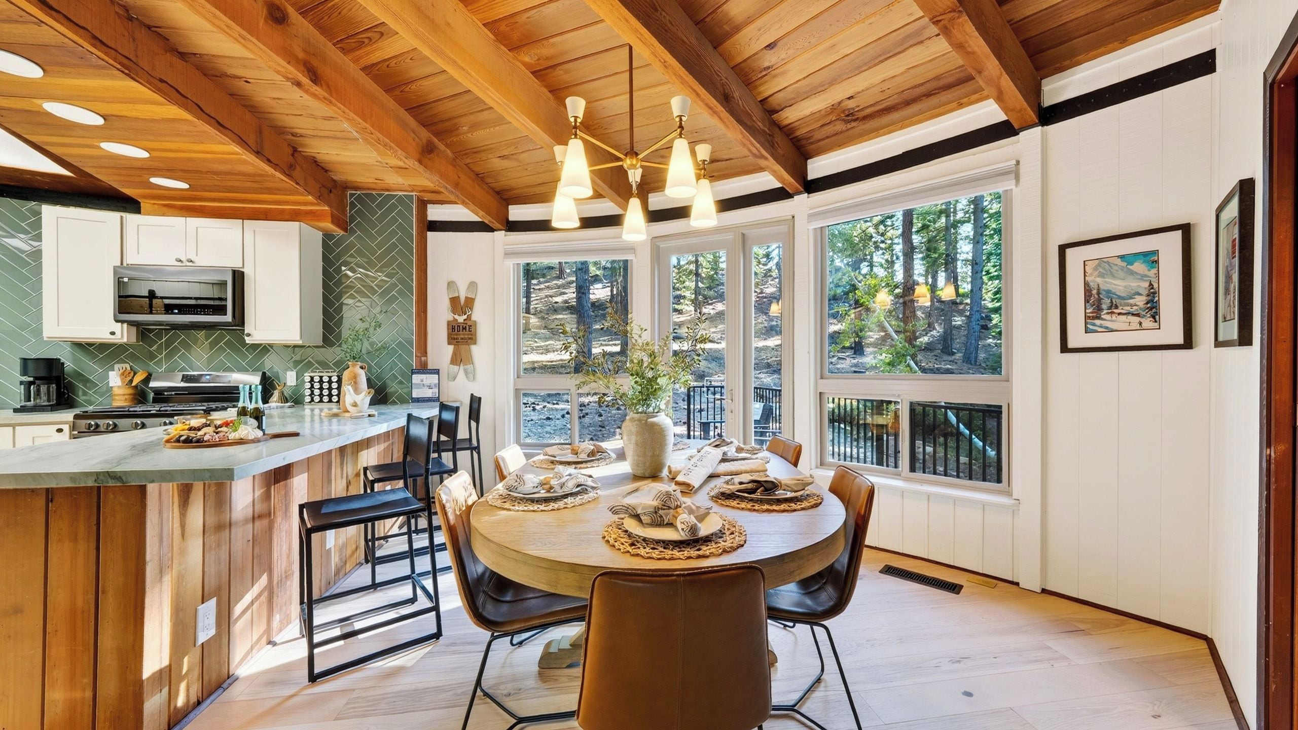 Cozinha moderna com teto de madeira, área de jantar com mesa redonda e grandes janelas com vista para o exterior.