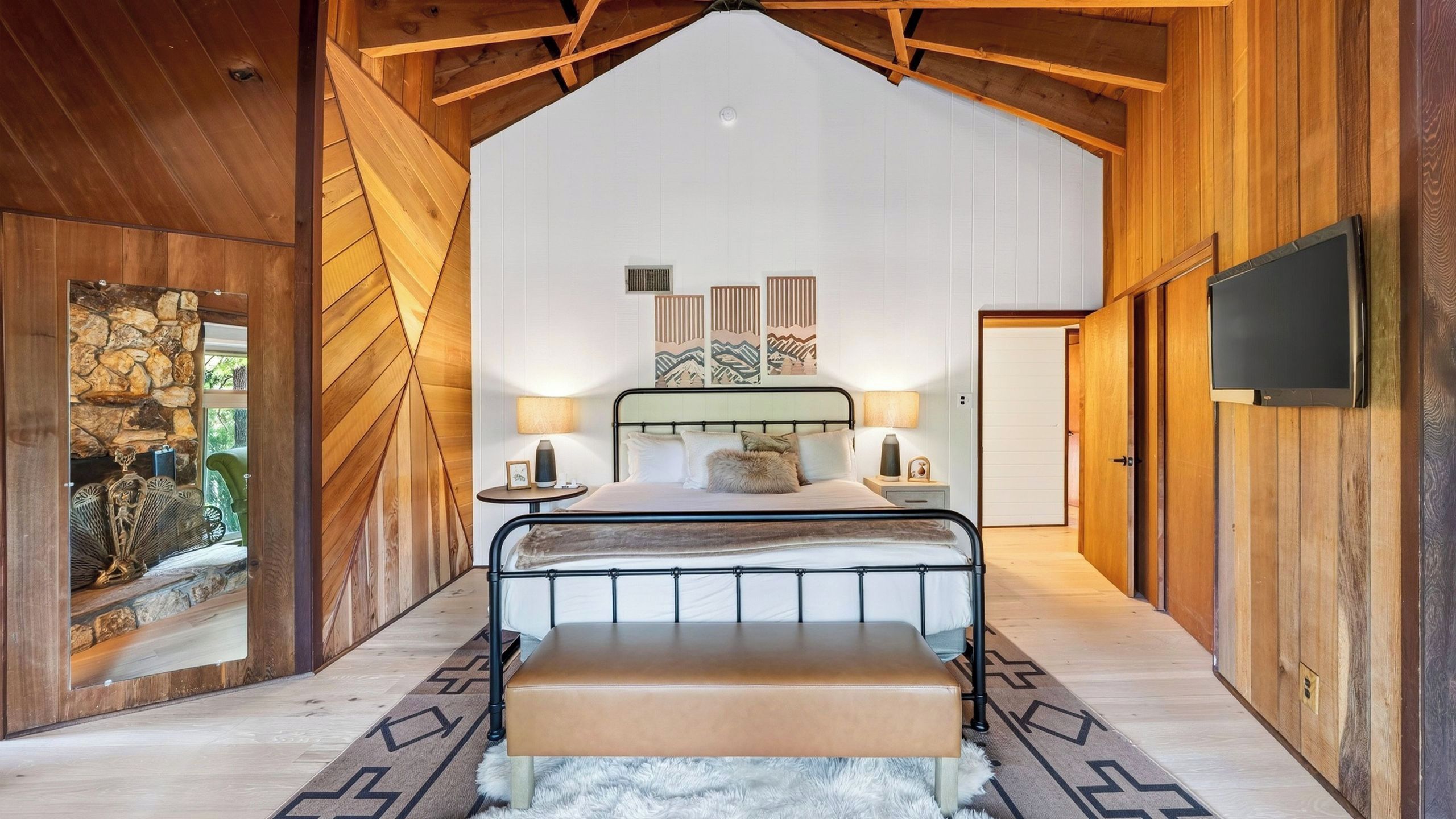 A spacious bedroom with a large bed, a bench, and a television.