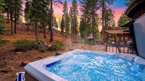 Ein Whirlpool mit Blick auf einen Wald und eine Holzhütte.