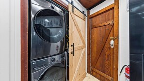 Ein kleiner Hauswirtschaftsraum mit einer Waschmaschine mit Frontlader und einer Holztür im Bauernhausstil.