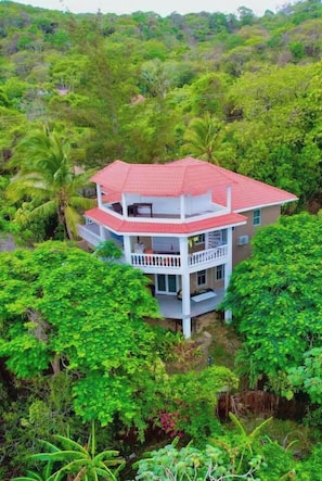 A two-story building with a red roof, surrounded by dense green foliage. - Your Own Private Resort in Roatán! (José Santos Guardiola)
