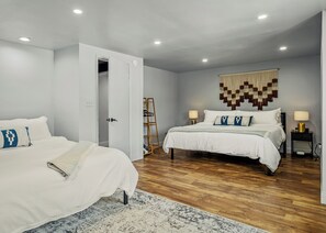 A bedroom with two beds, a wooden floor, a wall-mounted tapestry, and a ladder leaning against the wall. - Neon & Pop Retro Cabin w/ Sauna and Hot Tub
Neon & Pop (East Stroudsburg)