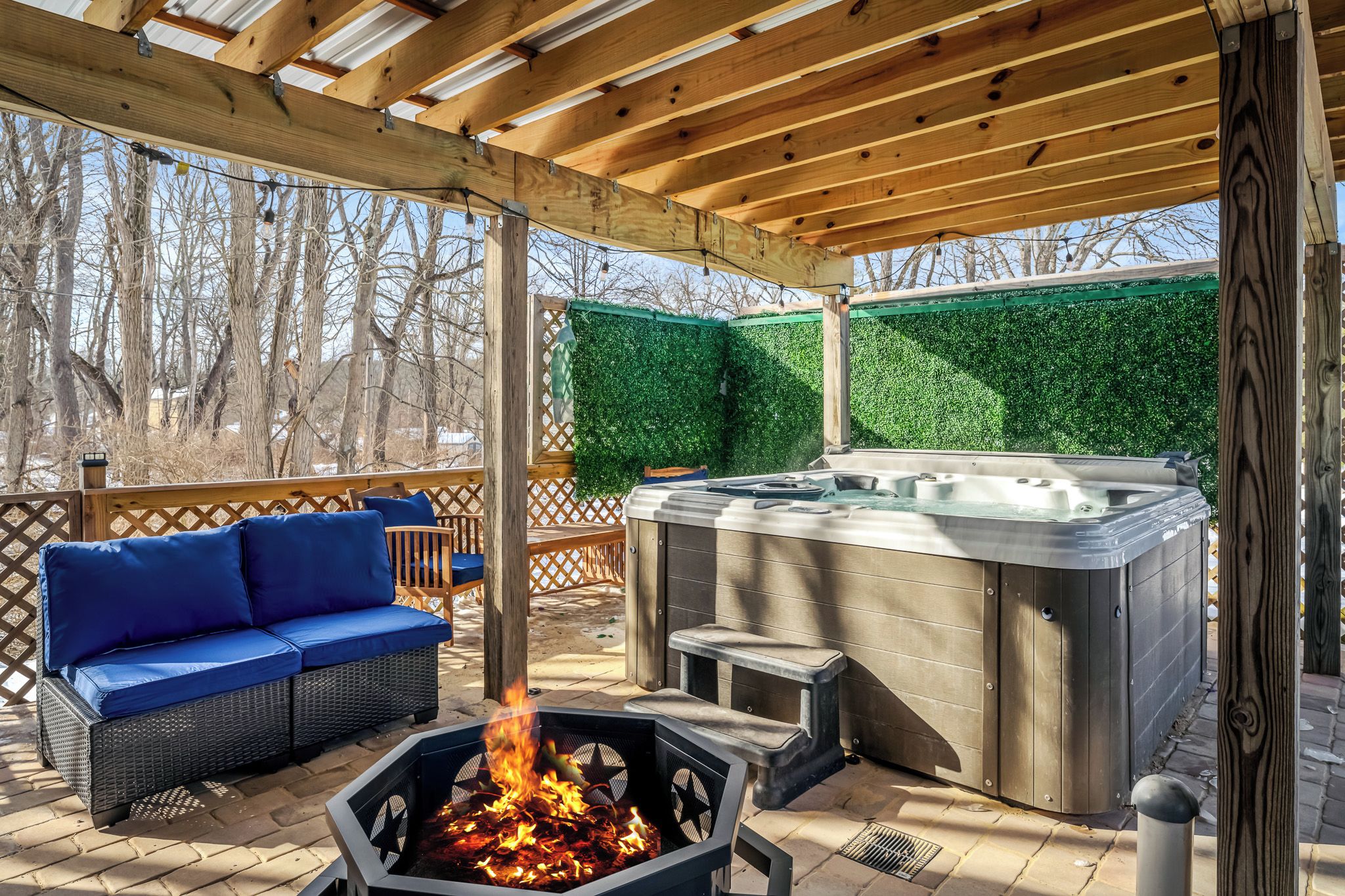 An outdoor patio with a hot tub, a fire pit, and a blue sofa.