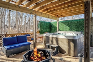 An outdoor patio with a hot tub, a fire pit, and a blue sofa.