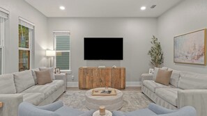 Ein modernes Wohnzimmer mit zwei Sofas, einem Couchtisch, einem Flachbildfernseher und einer Holzkommode.