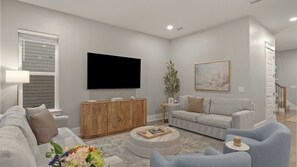 Ein modernes Wohnzimmer mit Flachbildfernseher, Holzschrank, grauem Sofa und Couchtisch.