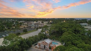 A large building with a parking lot and a swimming pool. - Maré 33 by Avantstay 6-seat Golf Cart + Arcade + Bunk Room Beach Walk + Pool (Miramar Beach)