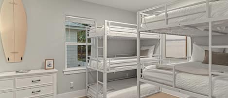 A bunk bed room with a surfboard on the wall, a dresser, and a window with blinds.
