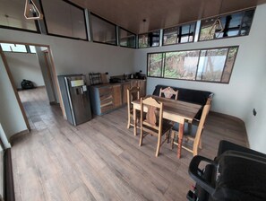 A modern kitchen with wooden cabinets, a stainless steel refrigerator, and a dining area with a wooden table and chairs.