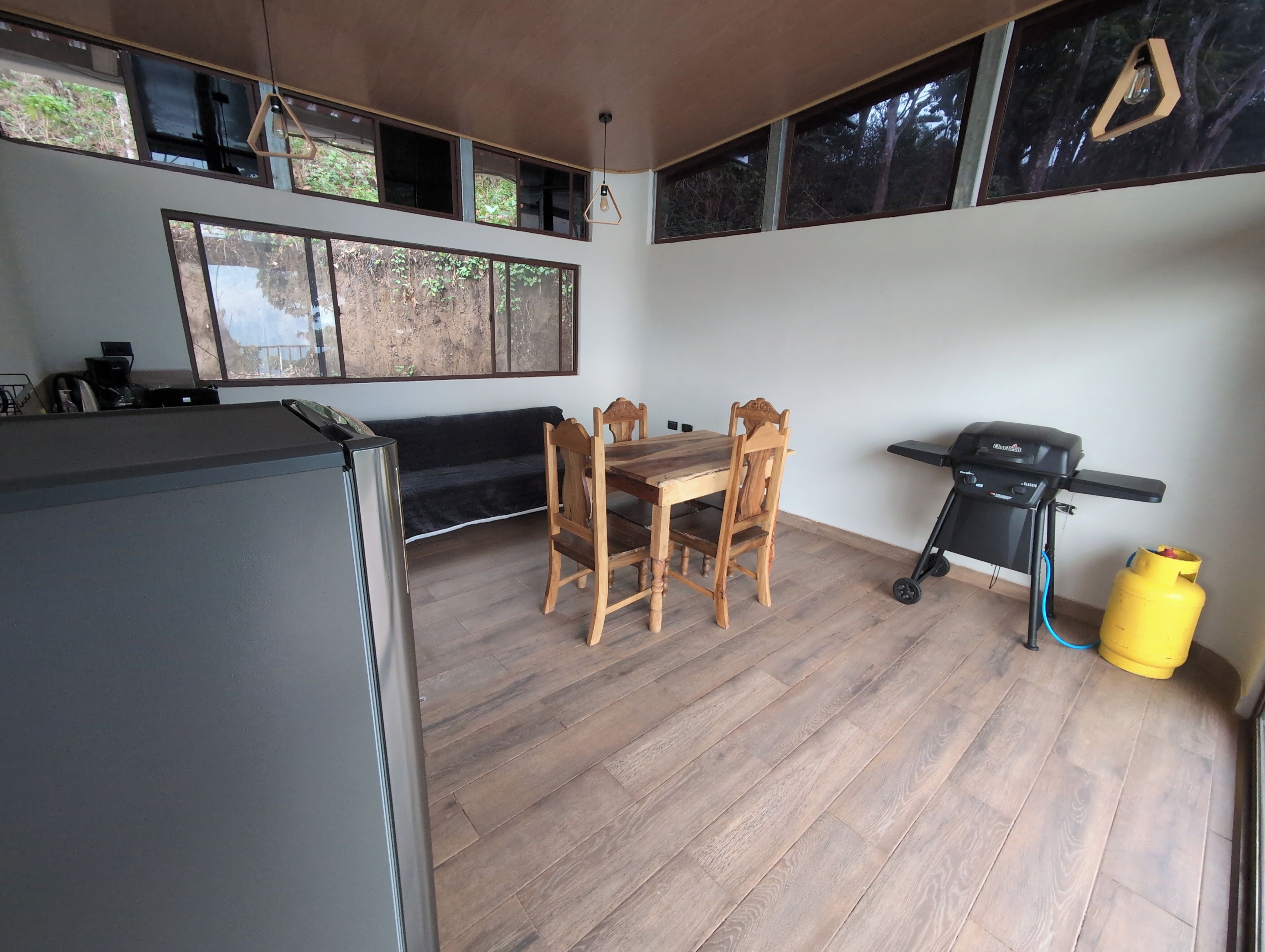 Una cocina con una mesa de comedor, sillas, una parrilla y un refrigerador.