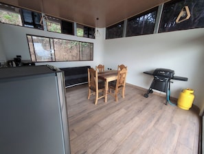 Una cocina con una mesa de comedor, sillas, una parrilla y un refrigerador.