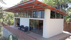A modern two-story building with a balcony, large windows, and a red roof.