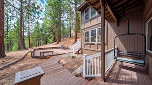 A wooden cabin with a deck, outdoor seating, and a staircase leading to a porch.