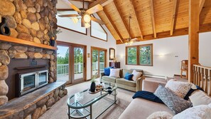 A spacious living room with a stone fireplace, a glass coffee table, and a comfortable seating area.