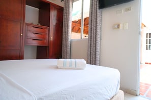 Habitació d'hotel amb un llit, un armari de fusta i una finestra amb cortines.