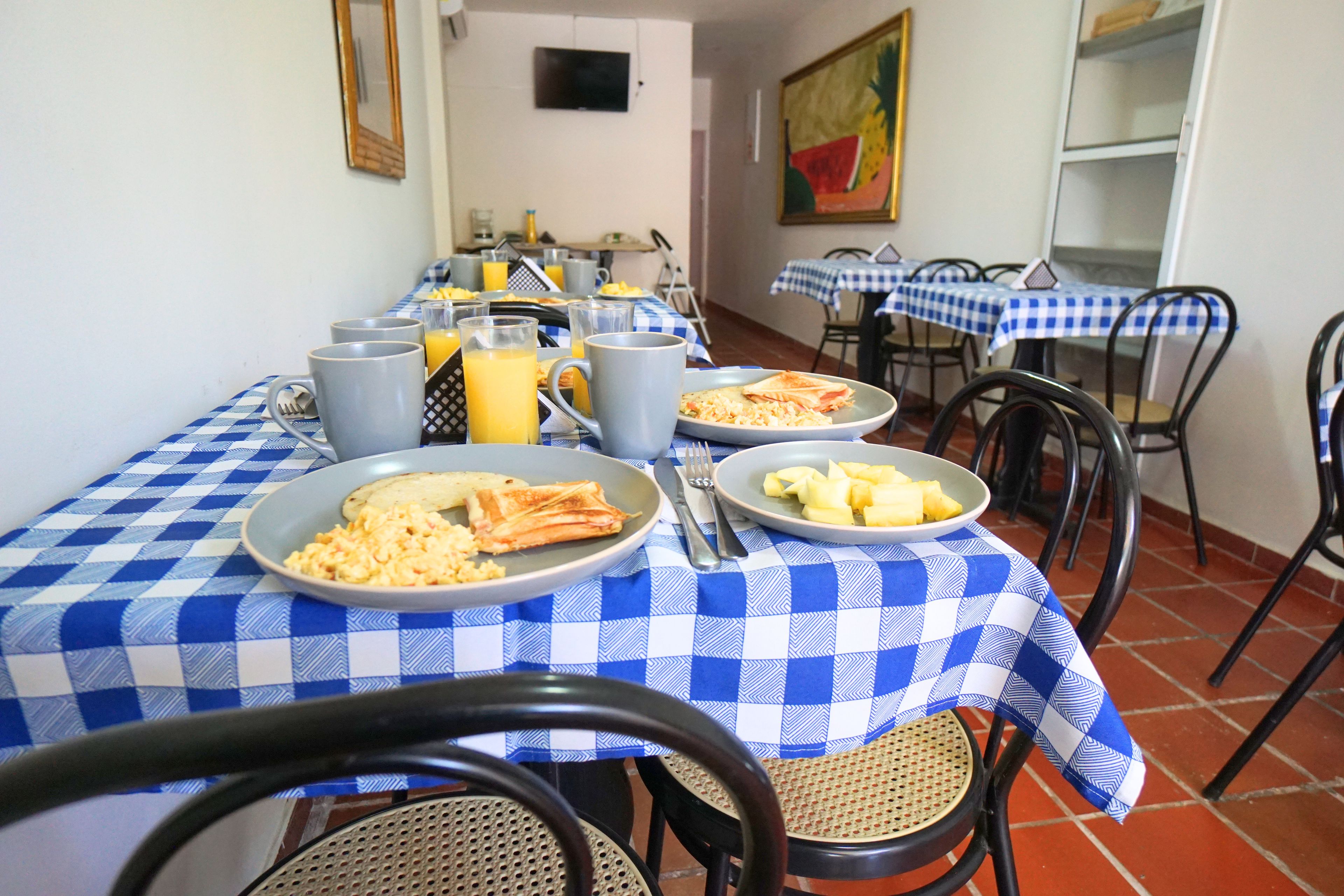 A dining area with checkered tablecloths, plates of food, and a television mounted on the wall.