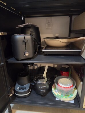 A kitchen with a toaster, a slow cooker, a pot, and a container of cake mix on the shelves. - Cozy studio apartment in tranquil Cutler Bay with AC and parking available (Cutler Bay)