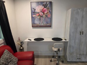 A room with a desk, a chair, a red sofa, a painting, and a wardrobe. - Cozy studio apartment in tranquil Cutler Bay with AC and parking available (Cutler Bay)