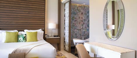 A hotel room with a large bed, a desk, a chair, a vanity, and a shower area.