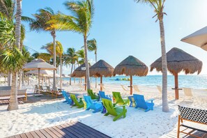 A beachside resort with thatched umbrellas, wooden deck, and colorful lounge chairs.