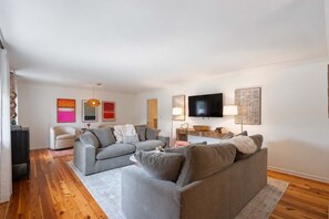 A modern living room with two grey sofas, a flat-screen TV, and a wooden coffee table. - Walk to Oxford Square | Sleeps 8 | Perfect for Ole Miss Getaways! (Oxford)