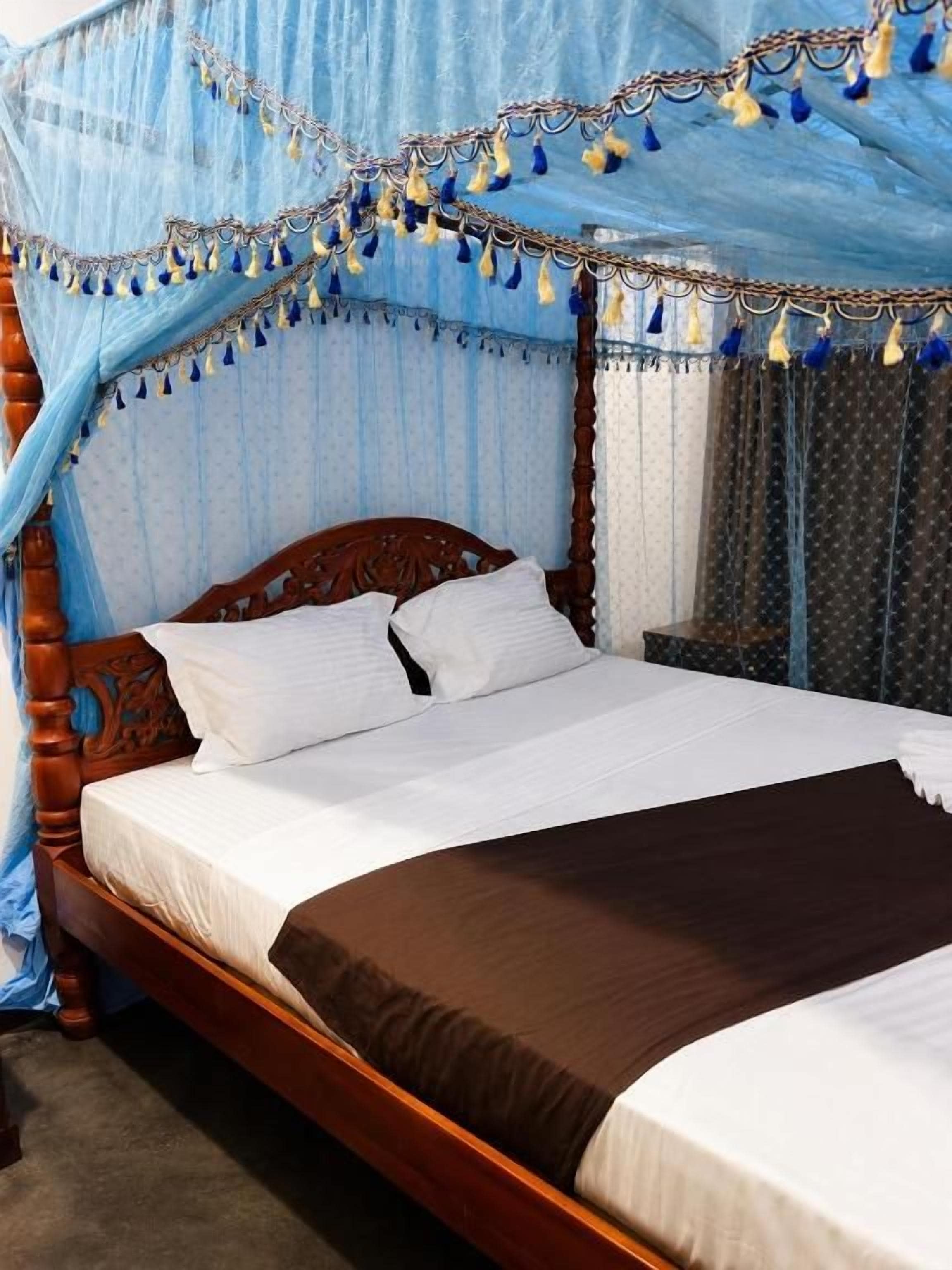 A four-poster bed with a canopy, wooden headboard, and white bedding.
