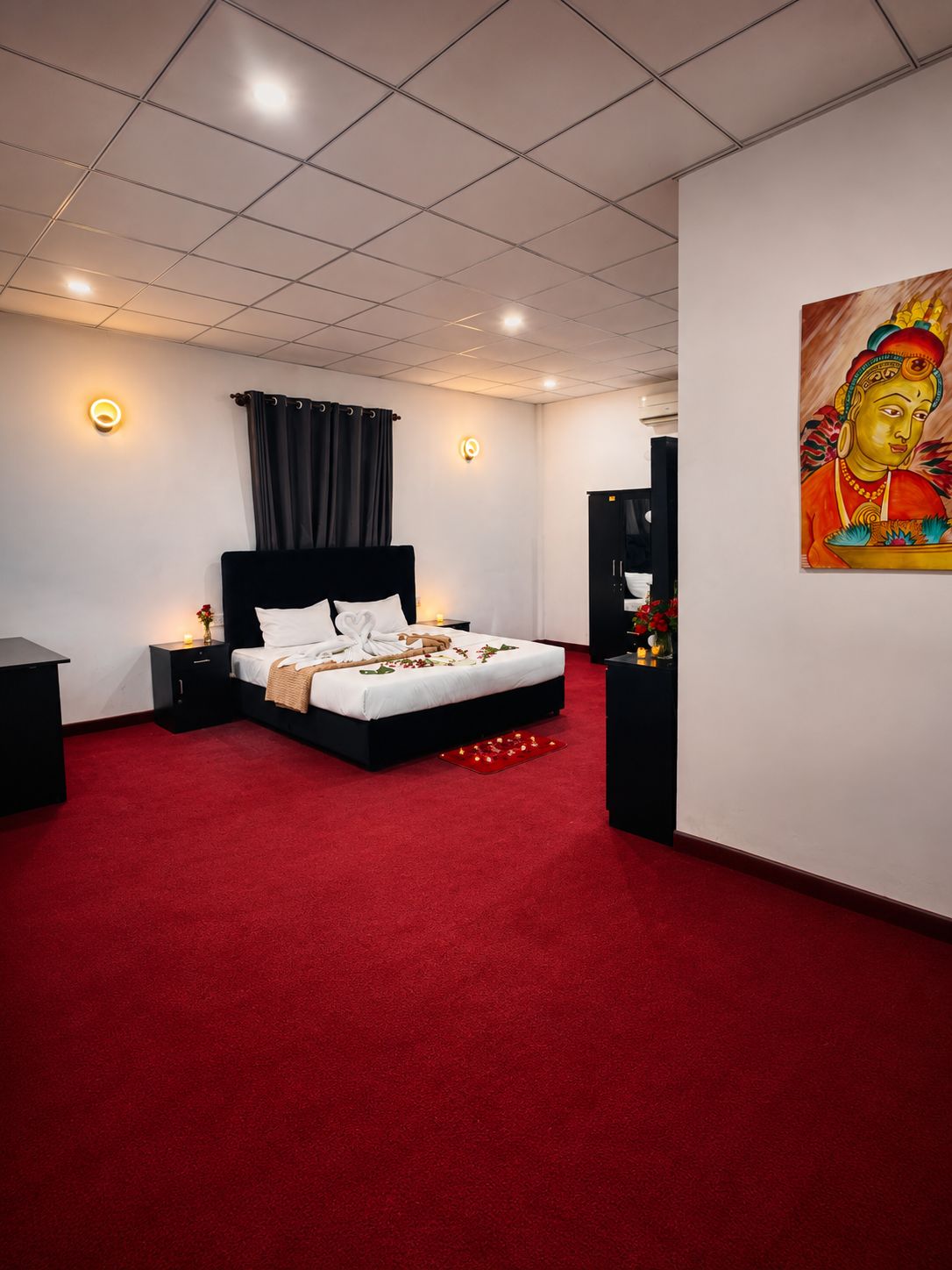 A hotel room with a large bed, a red carpet, a painting on the wall, and a television on a stand.