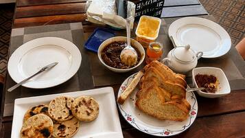 Una mesa servida con platos, pan, una tetera y condimentos.