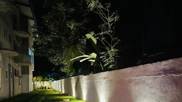 A nighttime view of a building with a well-lit pathway and a wall. - Amore Beach Resort (Balapitiya)