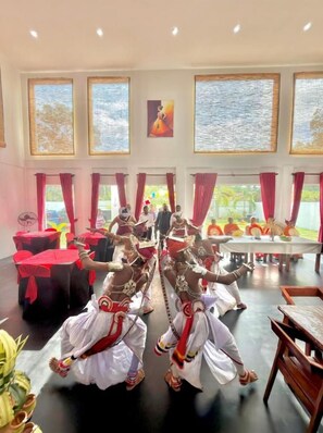 A room with large windows, a dining area, and a group of performers in traditional attire.