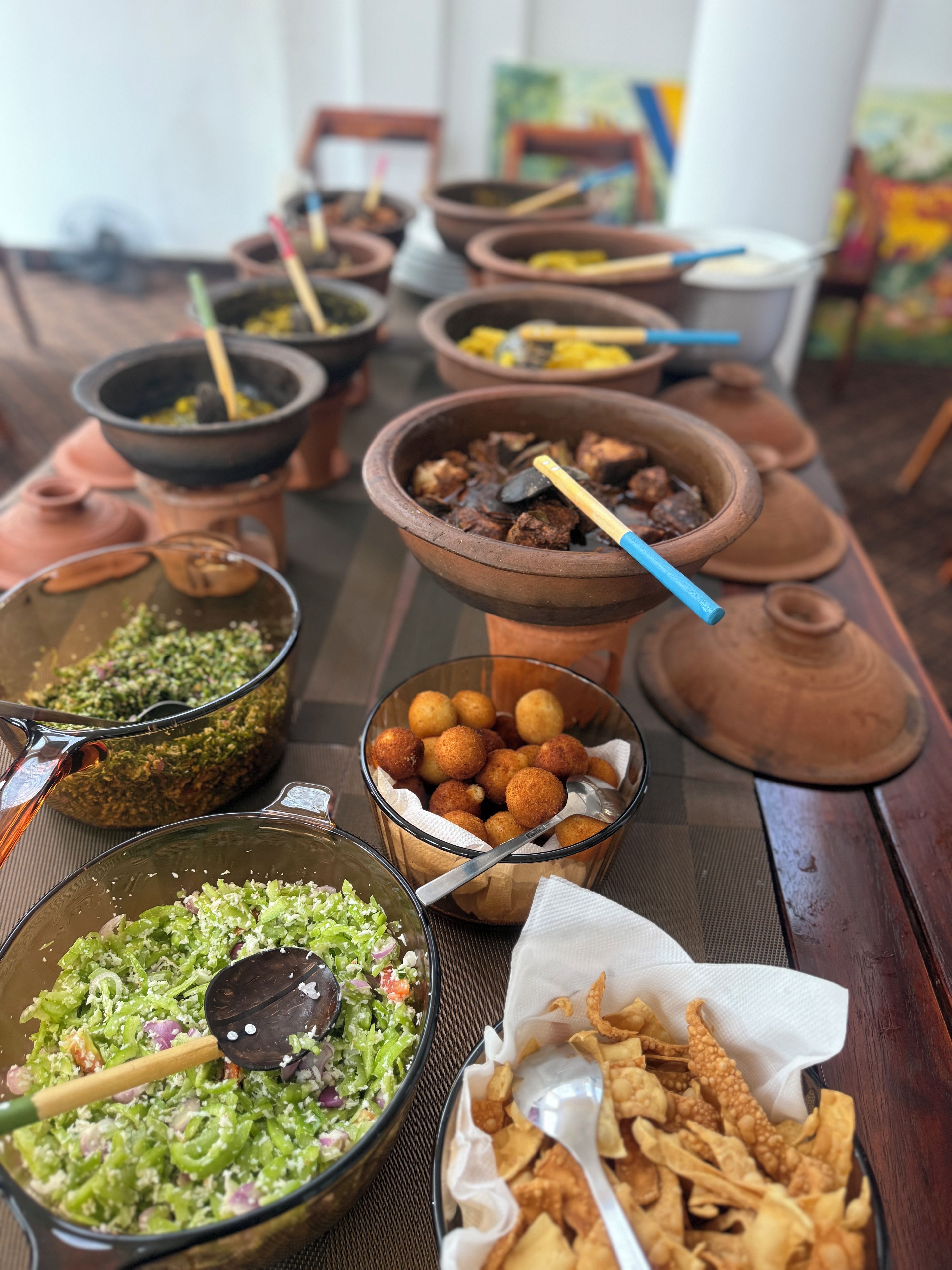 A table with various dishes, including a bowl of green salad and a bowl of fried items.