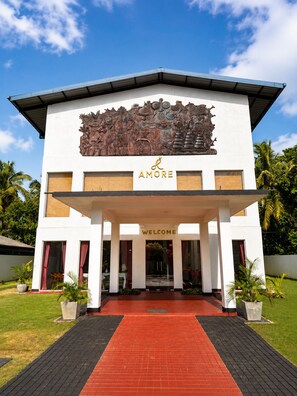 Un edificio moderno con un cartel de 'WELCOME', un gran relieve escultórico y el logotipo 'AMORE'.