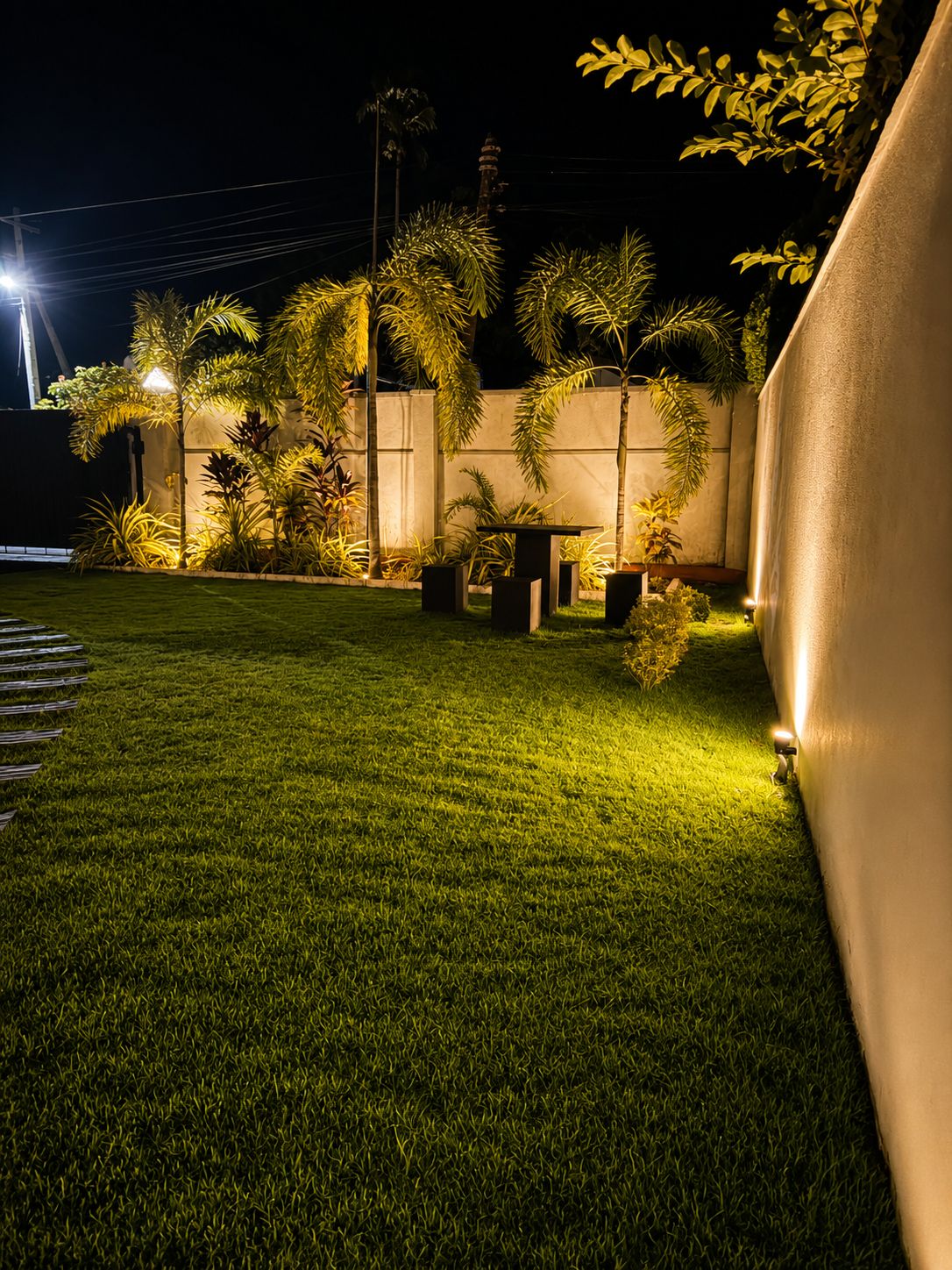 Un espacio exterior bien iluminado con un césped cuidado, una mesa y varias plantas en macetas.