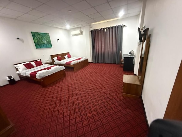 A hotel room with two beds, a red carpet, a painting on the wall, and a television on a stand.