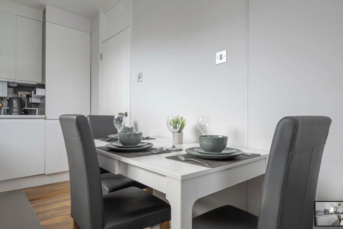 A modern dining area with a white table, grey chairs, and a minimalist design.