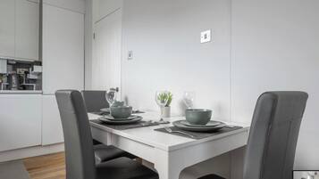 A modern dining area with a white table, grey chairs, and a minimalist design.