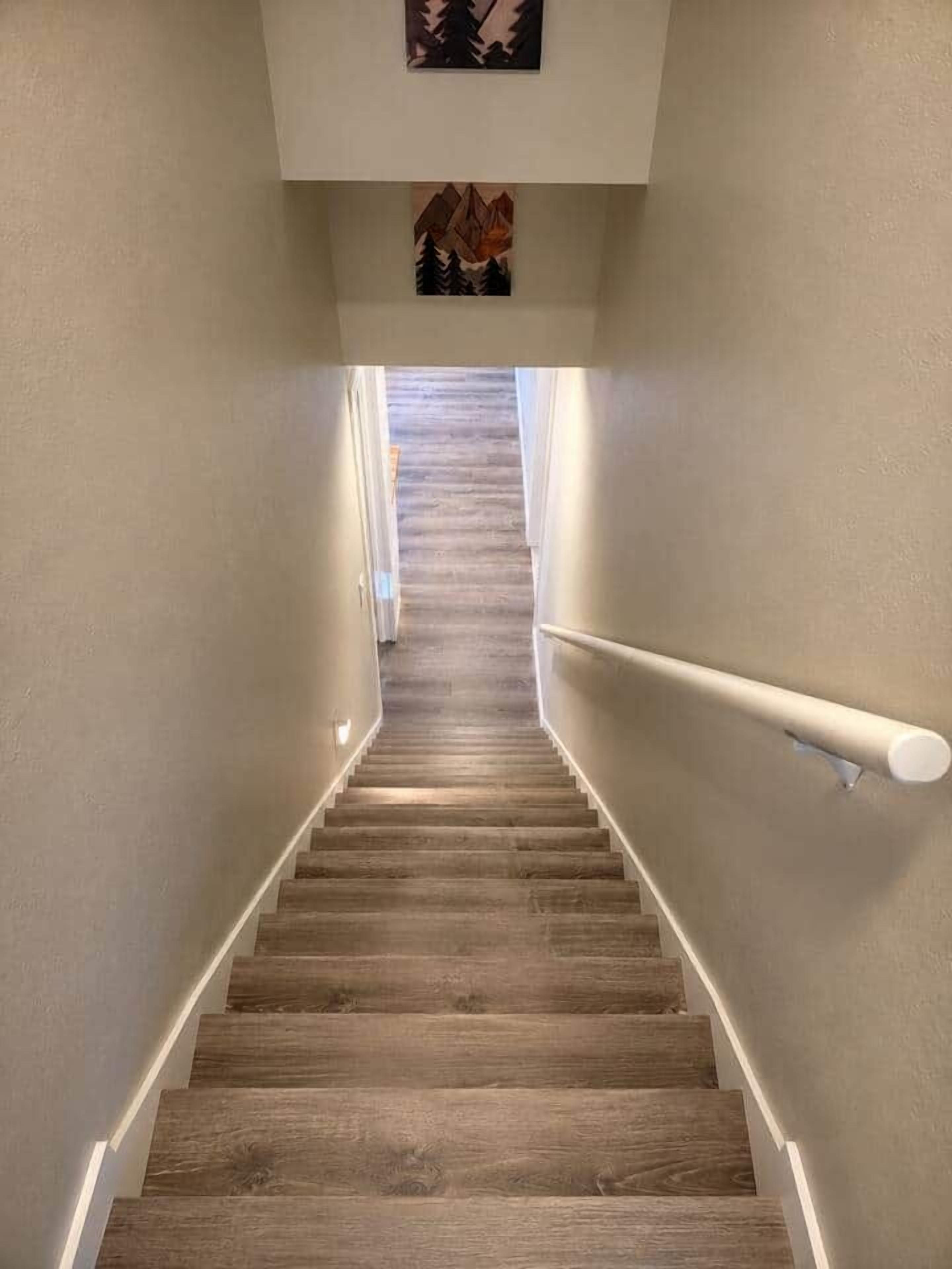Una escalera de madera con barandilla blanca que conduce a un rellano con un cuadro enmarcado.