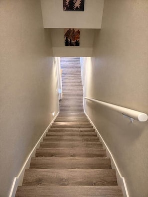 Eine Holztreppe mit weißer Handlauf, die zu einem Zwischenpodest mit einem gerahmten Bild führt.