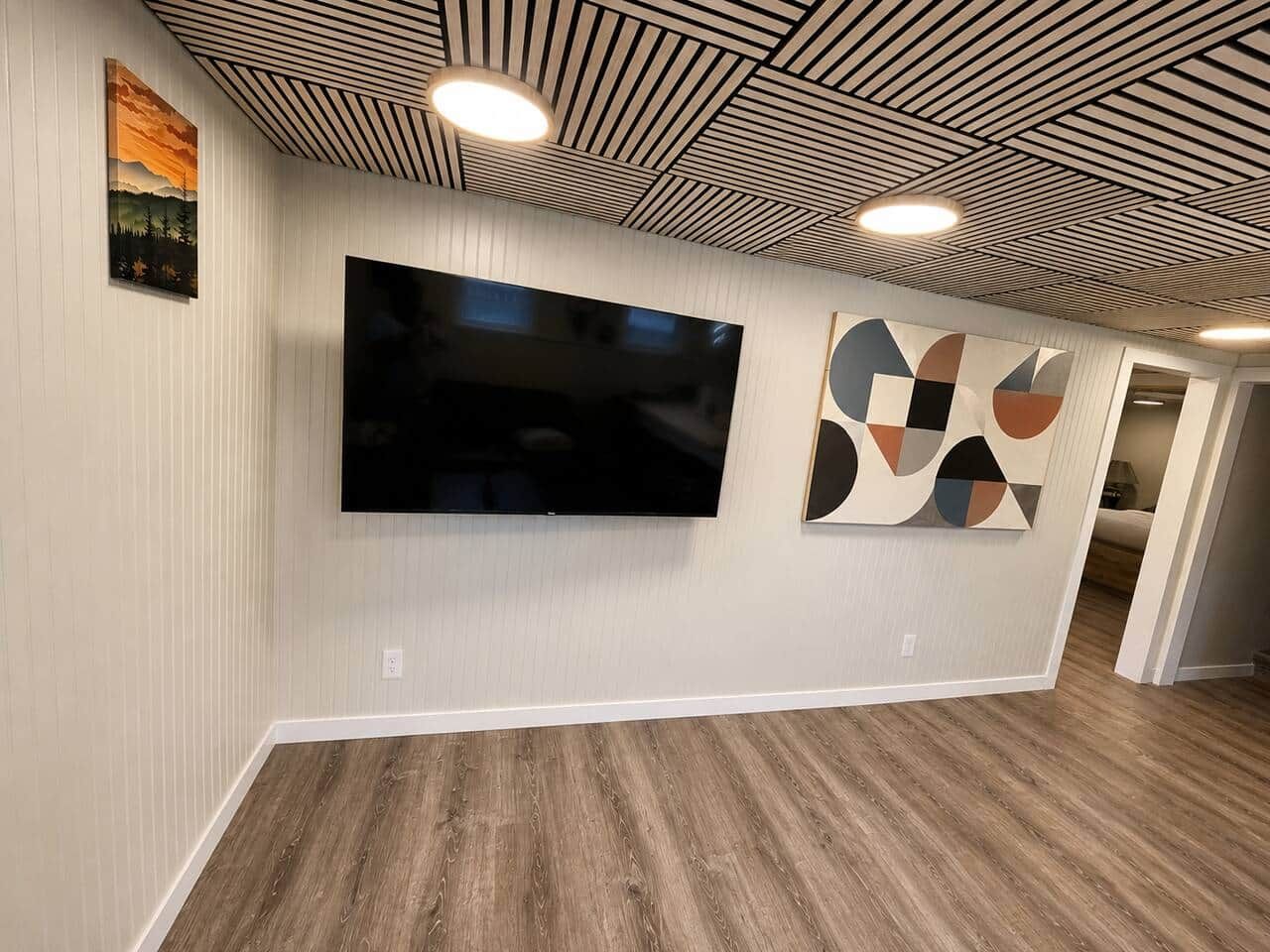 Un corridoio con una TV a schermo piatto montata al muro, un’opera d’arte geometrica e un soffitto a righe.