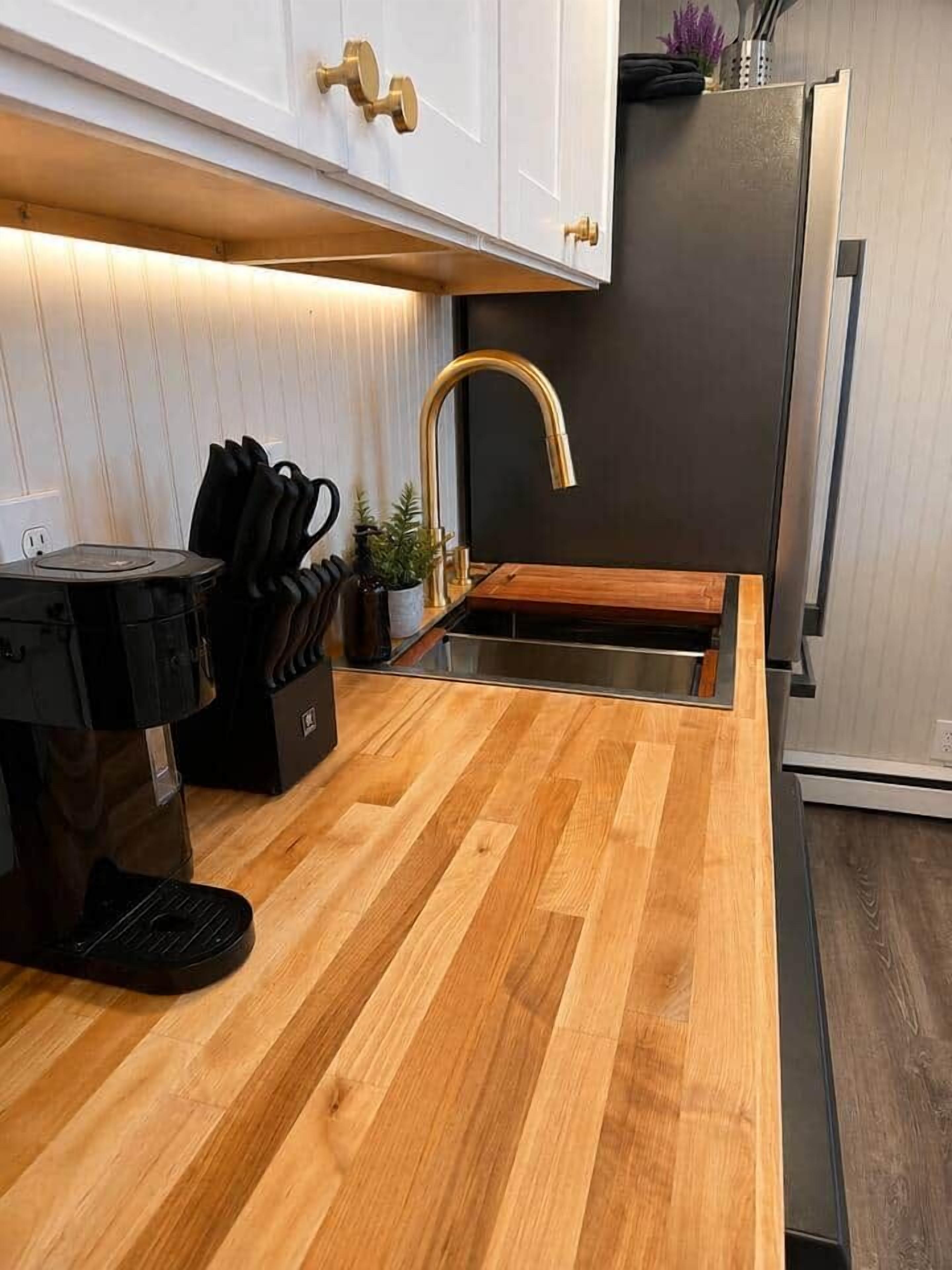 Une cuisine moderne dotée d’un plan de travail en bois, d’appareils électroménagers en acier inoxydable et d’un évier encastré.